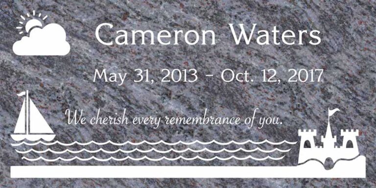 Granite grave marker with sailboat, sandcastle, waves, and sun