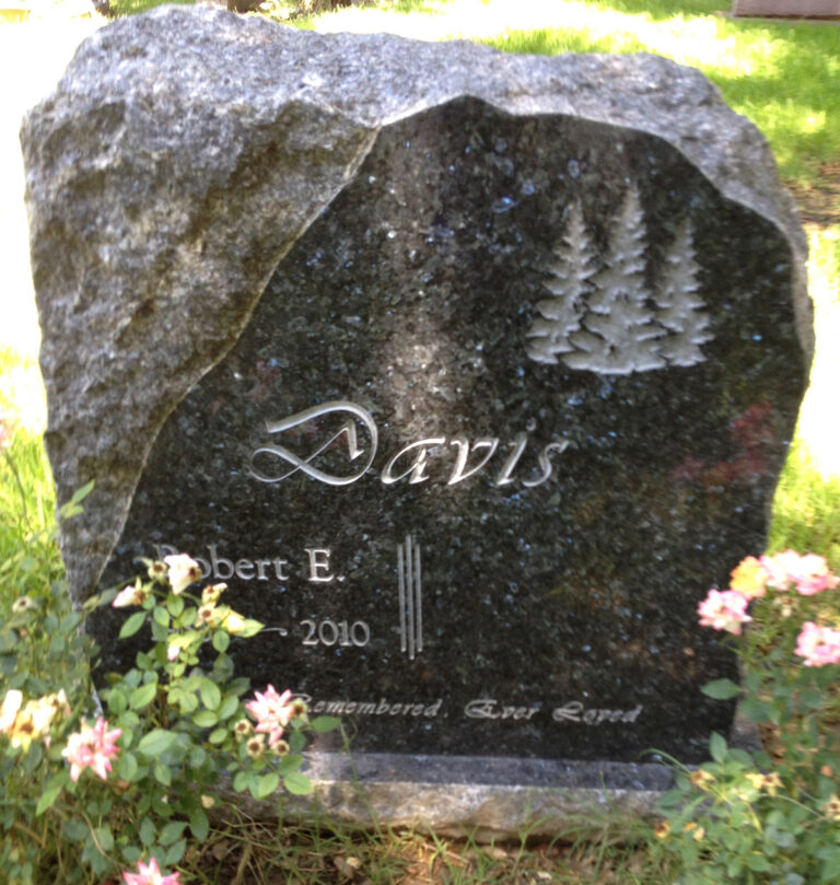 Granite monument in natural boulder shape with pine tree etching at Oak Park Cemetery in Claremont