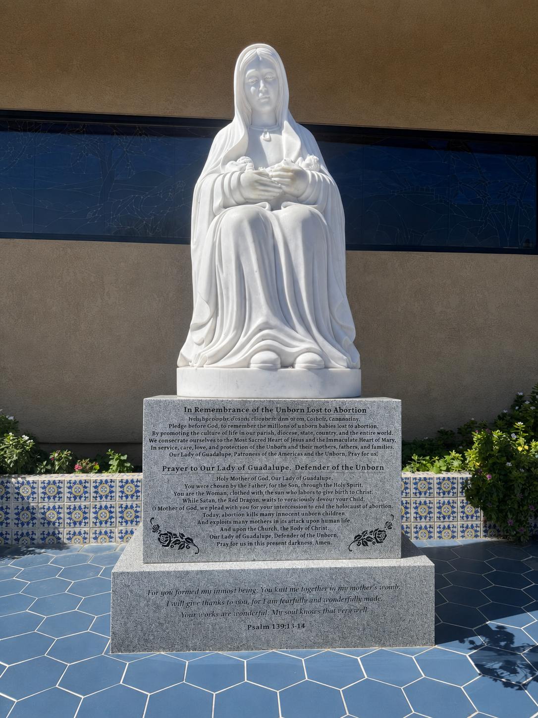 White marble statue of Our Lady of Guadalupe on an engraved granite base at St. Elizabeth Ann Seton Church, Ontario CA